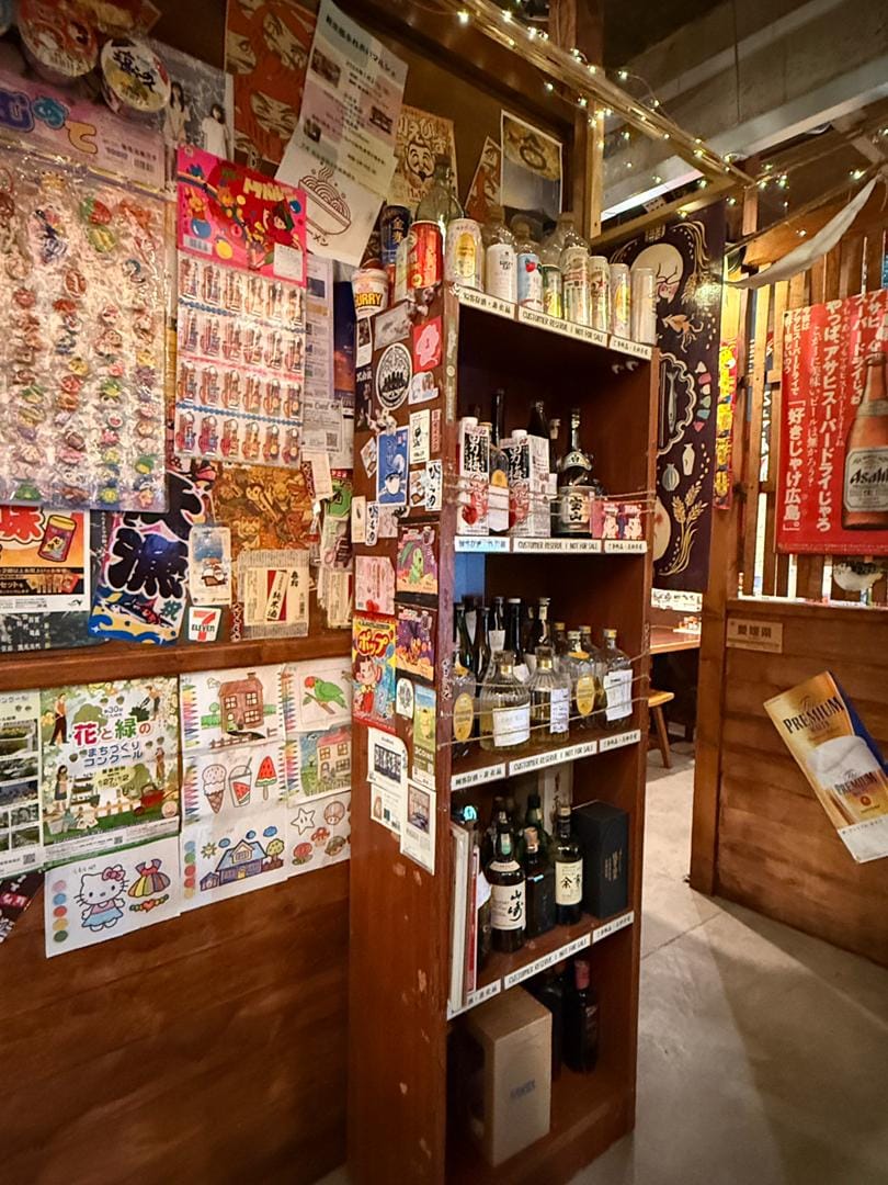 Showa-era poster wall and sake and shochu bottle shelf at Mount Austin